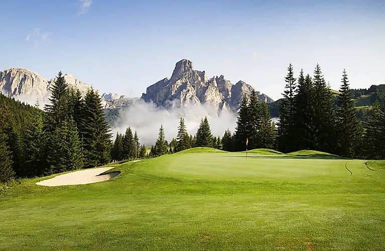 Un terrain de golf verdoyant dans un décor de montagne dramatique dans les Dolomites près de Corvara.