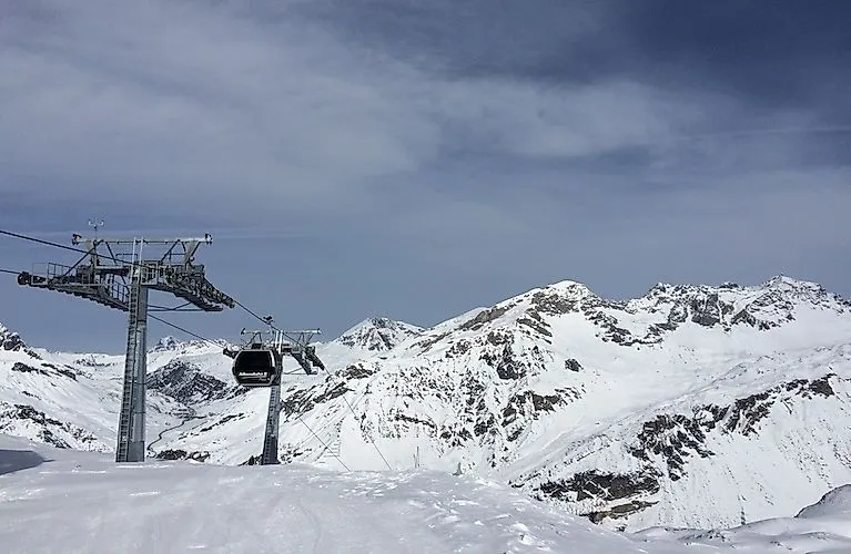 Albonabahn II gondola lift in the Stuben am Arlberg ski area with snow-covered mountains in the background