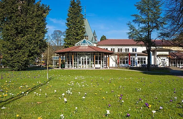 Frühling im Kurpark von Bad Herrenalb mit blühenden Wiesen und dem historischen Kurhaus im Hintergrund.