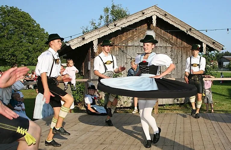 Grupo de trajes tradicionales interpretando danzas folclóricas bávaras en un escenario de madera en Bad Endorf
