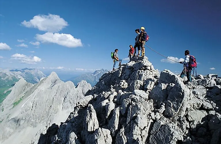 Gruppe klettert auf felsigem Gipfel bei St. Anton am Arlberg mit Bergblick