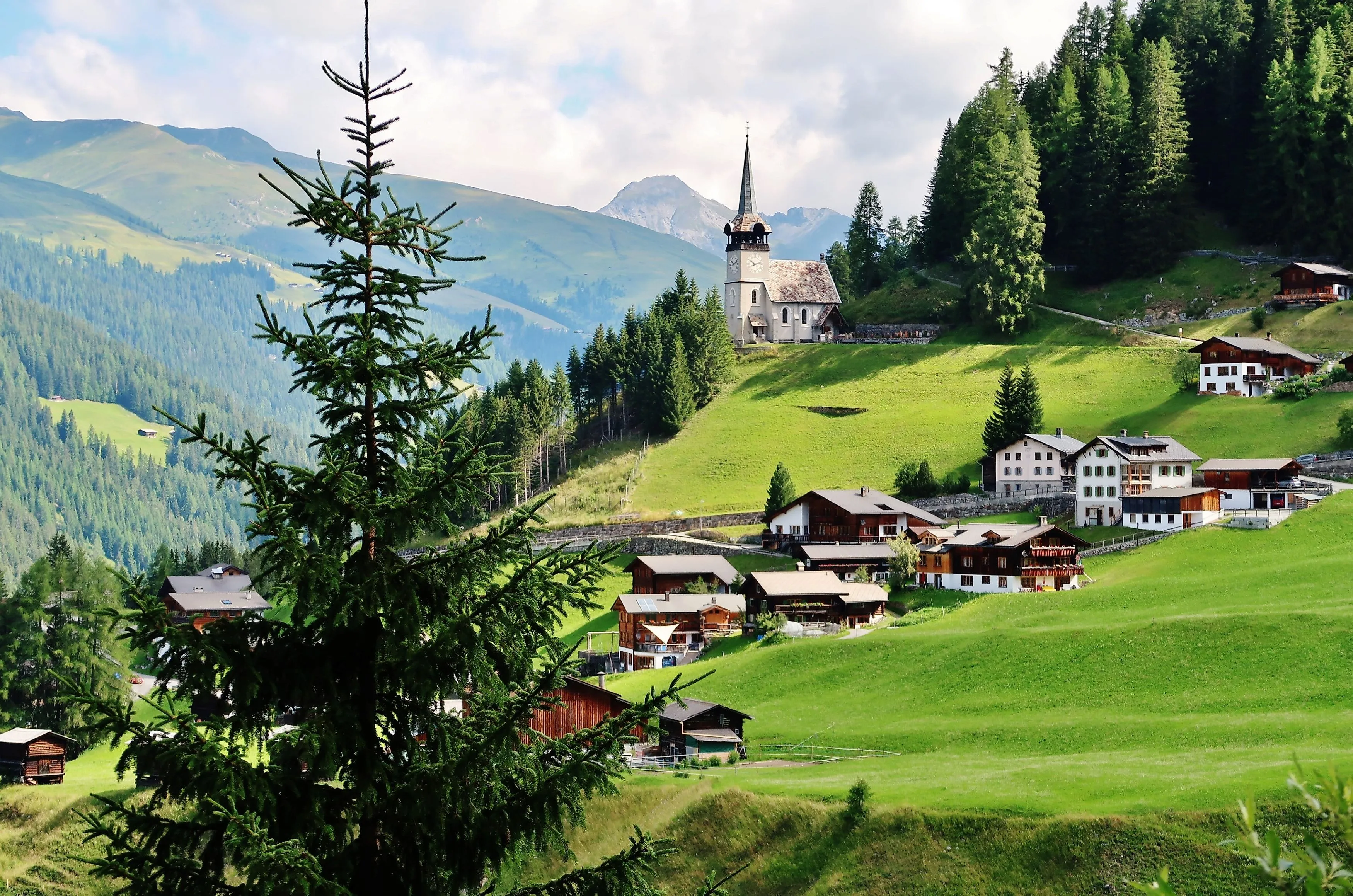 Dedina Davos Monstein s kostolom a drevenými domami v zelenej horskej krajine Graubündenu