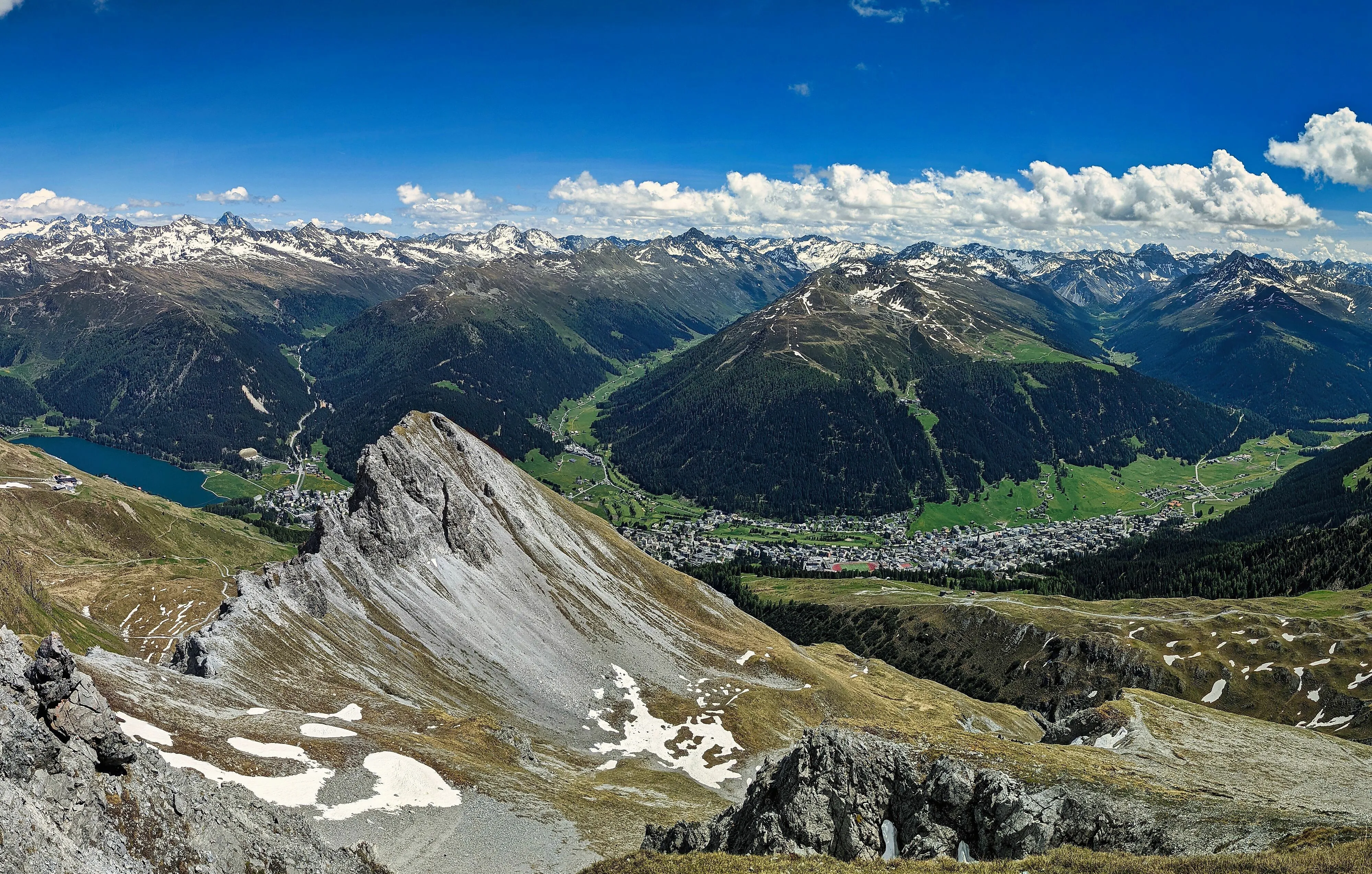 Panoramisch uitzicht op Davos-Dorf en het omliggende Alpenlandschap met meer, dalen en besneeuwde bergtoppen.