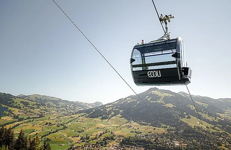 Moderne Gondelbahn Eggli schwebt über sommerliche Alpenlandschaft bei Gstaad