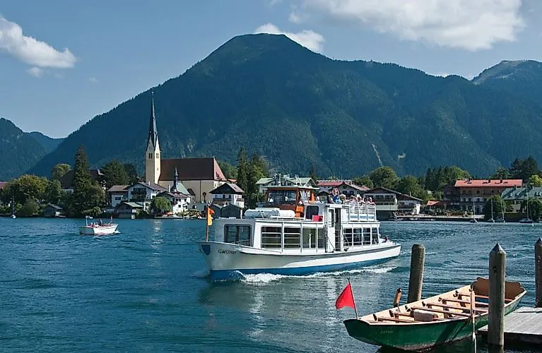 Excursion boat on Lake Tegernsee with a view of the village and the surrounding mountains on a sunny summer's day.