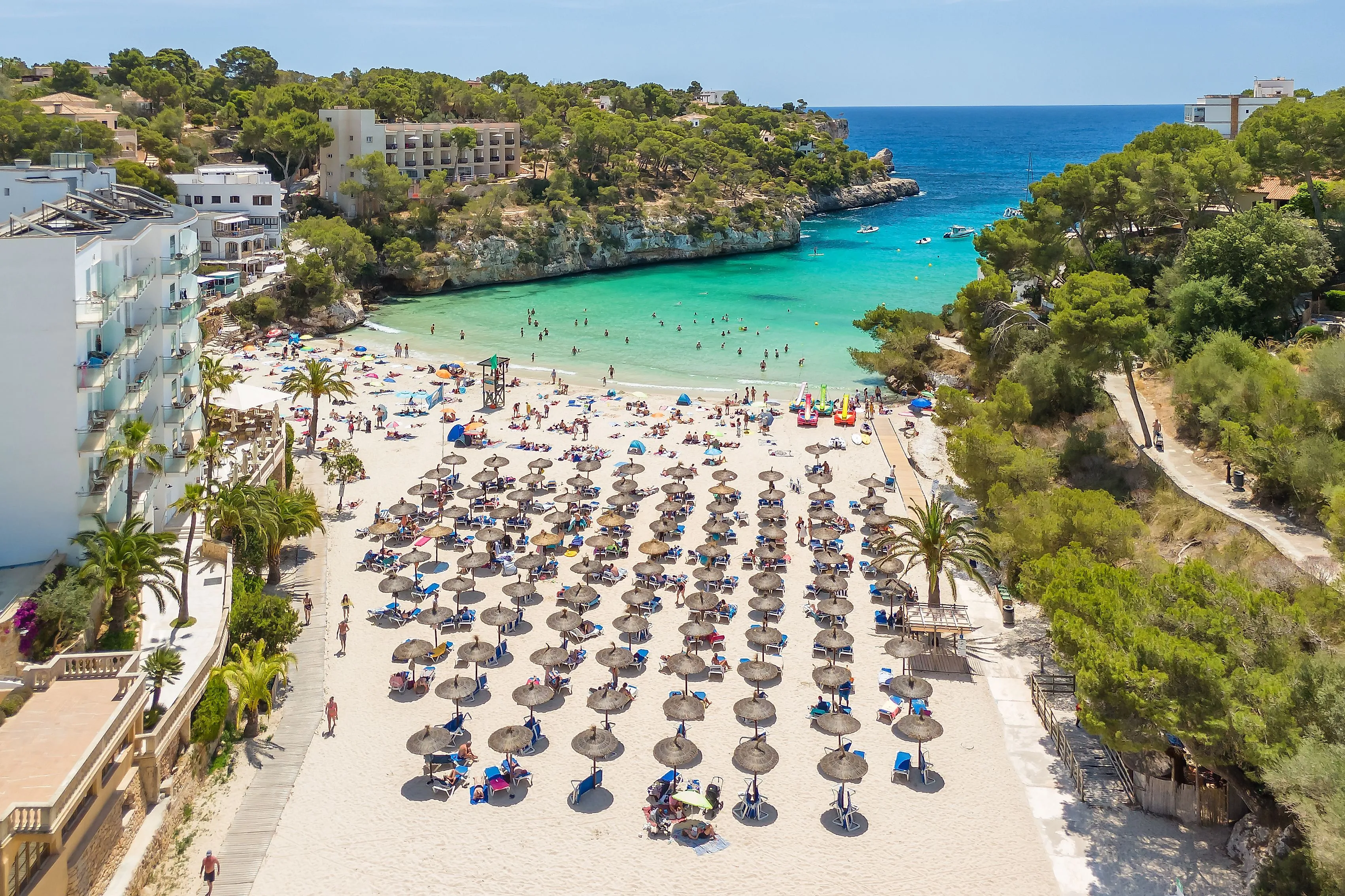 Lively sandy beach Cala Santanyí with parasols, bathers and crystal-clear water on Mallorca.