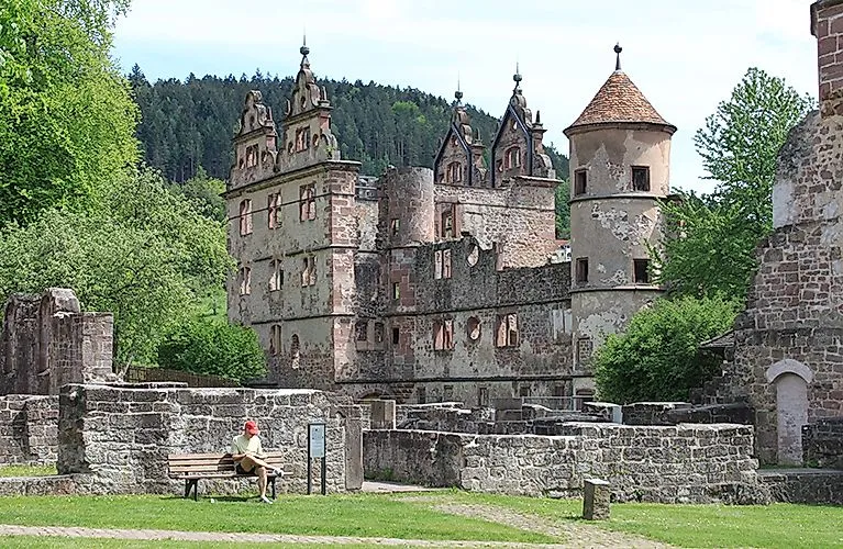 Zřícenina opatství Hirsau u Calwu s návštěvníky na lavičce v parku