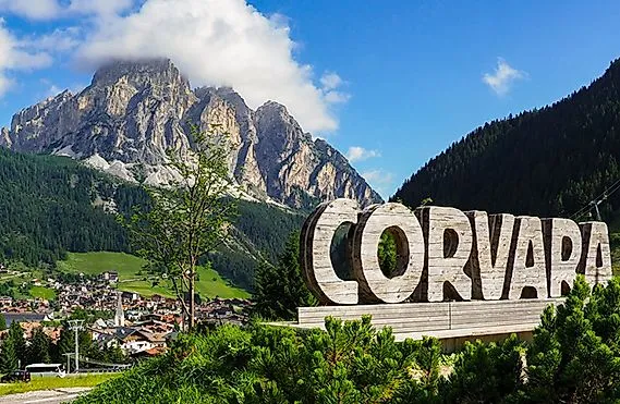 Vue sur le village de Corvara en été, entouré de vertes prairies et des impressionnants sommets des Dolomites.