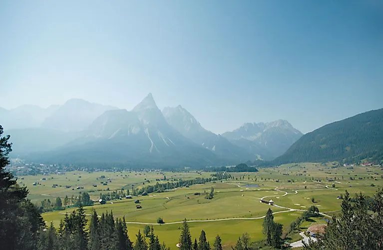 Rozsáhlé údolí u Ehrwaldu s výhledem na impozantní Zugspitze v pozadí za jasného letního dne.