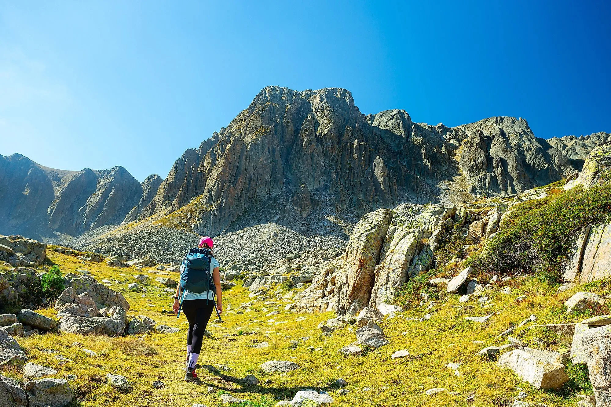 Wanderin mit Rucksack vor steilen Felswänden in den Pyrenäen bei Encamp, Andorra