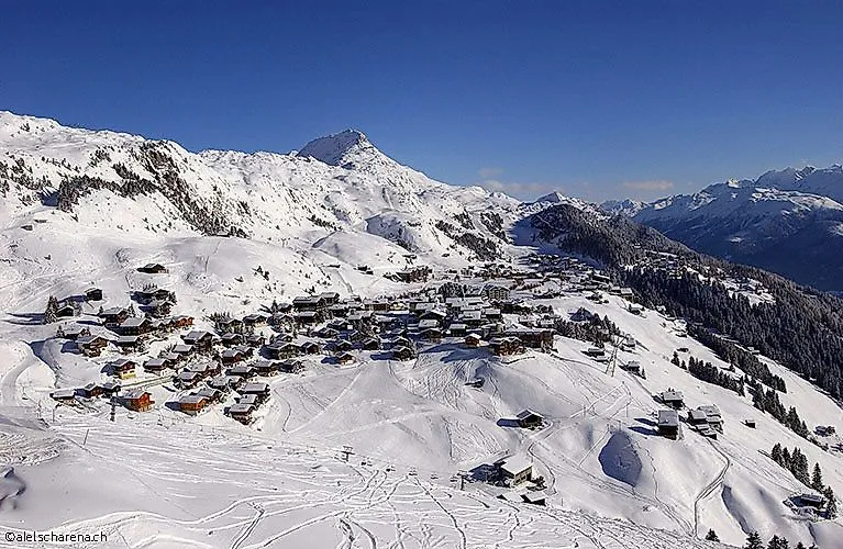 Aerial view of the snow-covered mountain village of Fiescheralp with surrounding winter landscape and mountain panorama.