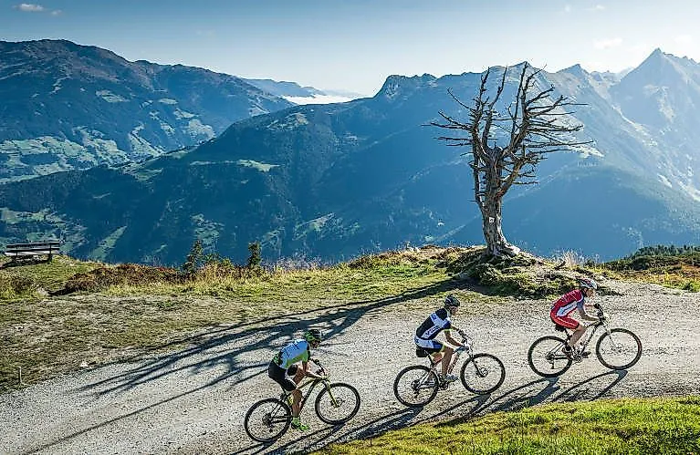 Tres ciclistas de montaña recorren bajo el sol un sendero panorámico en los Alpes tiroleses, cerca de Fügen.