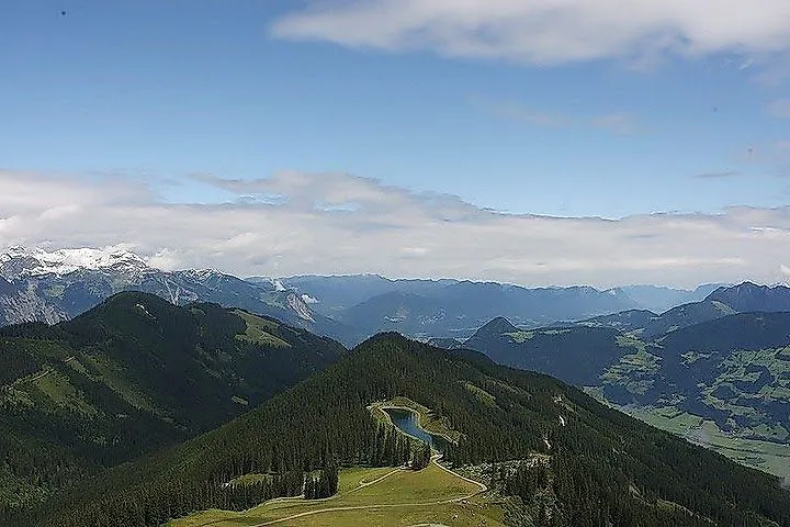 Vista del Spieljoch cerca de Fügen con verdes pastos de montaña, bosques y vistas lejanas de los Alpes Zillertal.