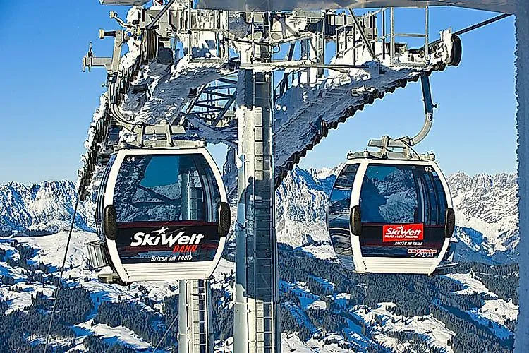 A gondola lift at SkiWelt Wilder Kaiser Brixental with two cabins against a snow-covered mountain landscape
