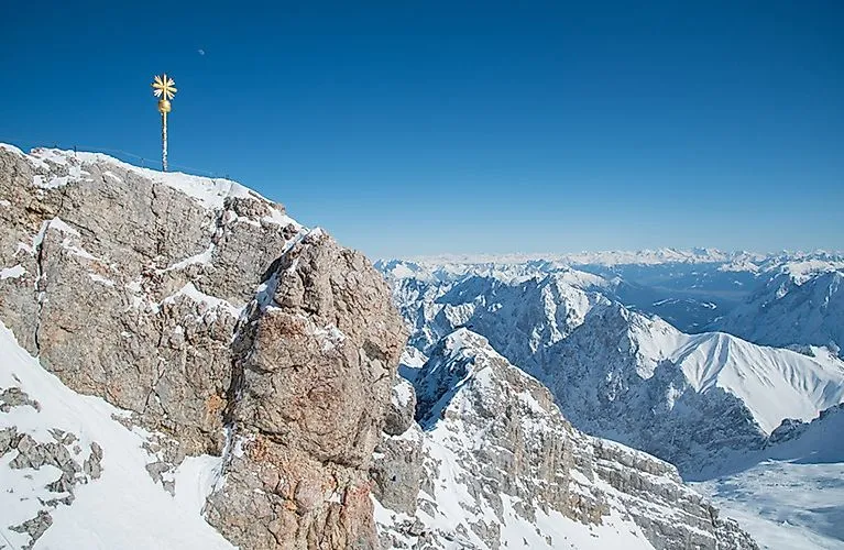 Schneebedeckte Gipfel der Zugspitze mit Gipfelkreuz und weitem Panoramablick im Winter.