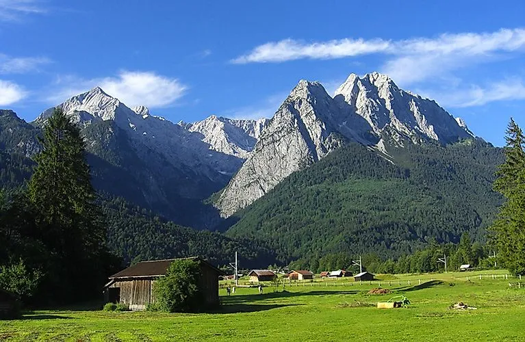 Uitzicht op zomerse groene weiden in Grainau, Beieren, met de ruige toppen van de Zugspitze op de achtergrond