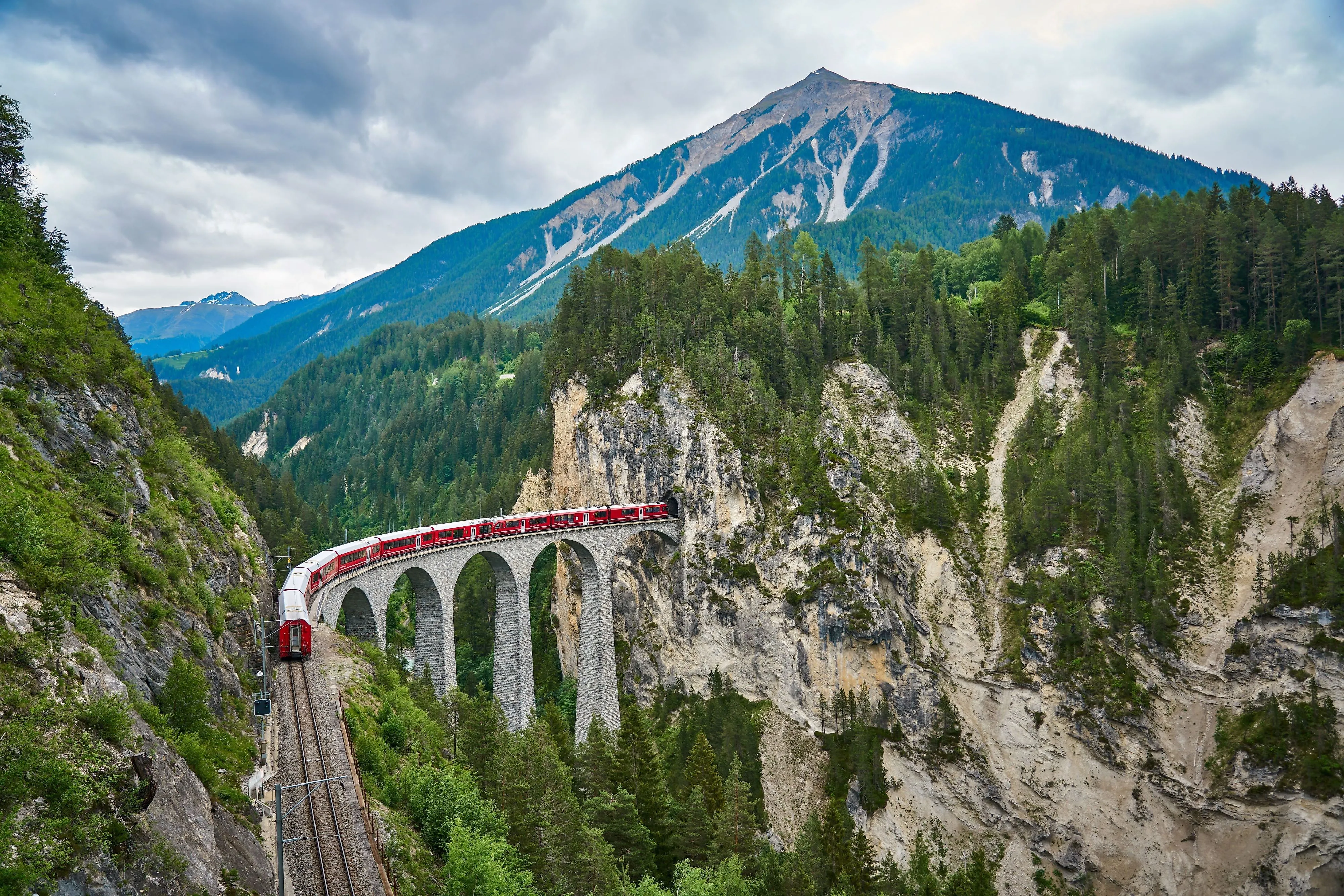 Bernina Express na viaduktu obklopeném nádhernými alpskými scenériemi v Graubündenu