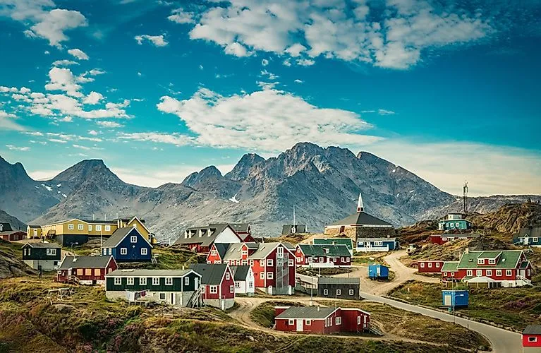 Coloridas casas de madera en Tasiilaq con el majestuoso telón de fondo de las montañas de Groenlandia en verano