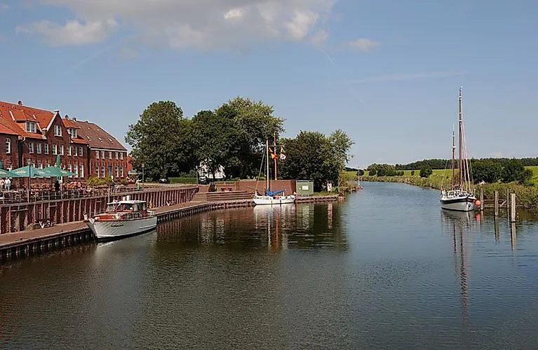 Bateaux dans le port idyllique de Hooksiel devant des maisons en briques et des arbres par une journée ensoleillée