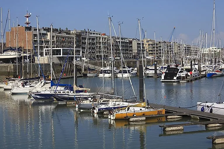 View of the Zeebrugge marina with numerous sailing boats and yachts, in the background modern residential buildings along the quay wall.