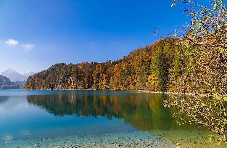 Alpsee near Schwangau in the fall, with calm waters, wooded shores, and mountains in the background