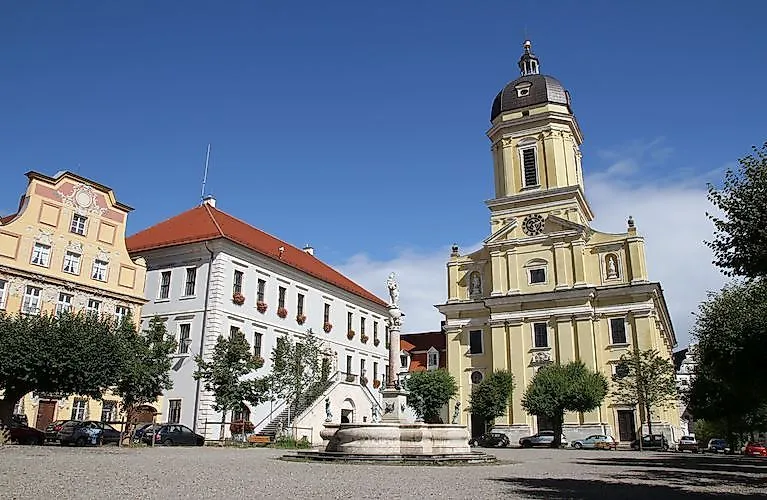 Barocke Hofkirche mit Brunnen auf dem Karlsplatz in Neuburg an der Donau bei sonnigem Wetter