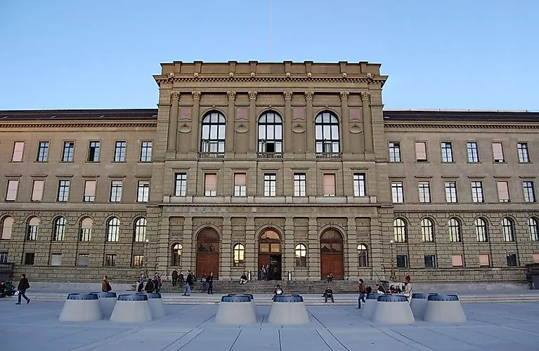 Het historische hoofdgebouw van de ETH Zürich met mensen op het voorplein op een heldere dag.