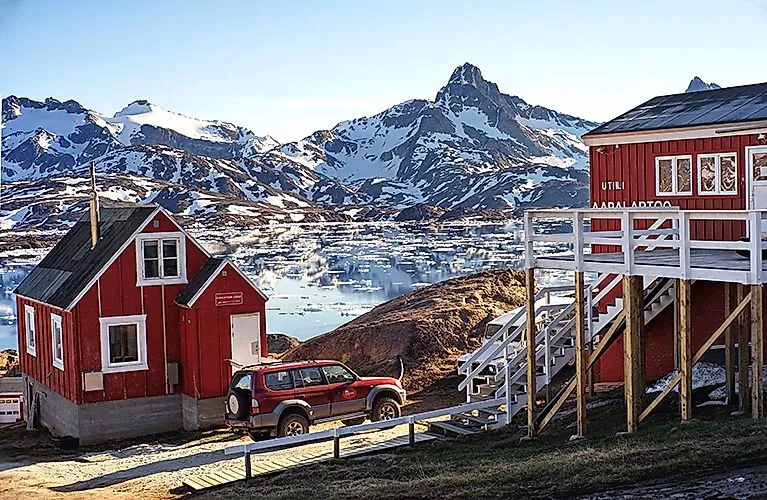 El hotel "The Red House" con casas de madera rojas frente a montañas nevadas en Tasiilaq, Groenlandia Oriental