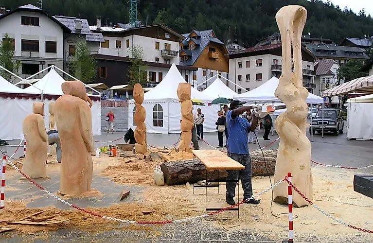 Mann schnitzt Holzskulptur auf Platz in Tarvisio bei Kunsthandwerksveranstaltung im Sommer