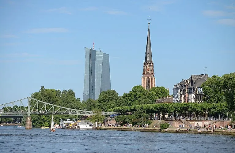 View of the Eiserner Steg, the banks of the Main and the Frankfurt skyline with the ECB and the Dreikönigskirche in the background.