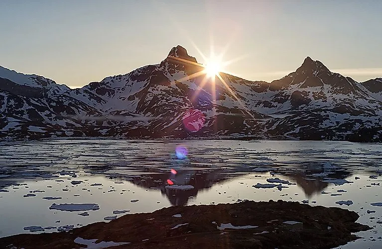 Puesta de sol sobre montañas nevadas y témpanos de hielo en la bahía de Tasiilaq