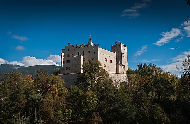 Hrad Bruneck v Južnom Tirolsku na zalesnenom kopci nad mestom v údolí Puster