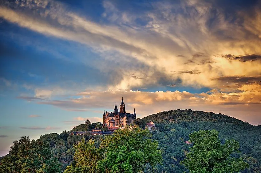 Fairytale Wernigerode Castle at sunset on a wooded hill in the Harz Mountains.