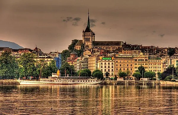 Historické staré město Ženeva s katedrálou St Pierre a osvětlenou promenádou u jezera