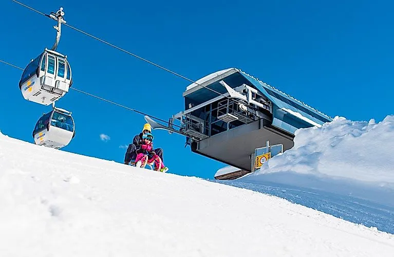 Kinder beim Rodeln nahe der Bergstation Sonnenkopf im Klostertal mit Gondelbahn im Hintergrund