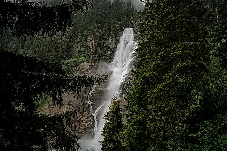Krimmlské vodopády v Národním parku Vysoké Taury, vysoký vodopád mezi hustými jehličnatými lesy v rakouských Alpách