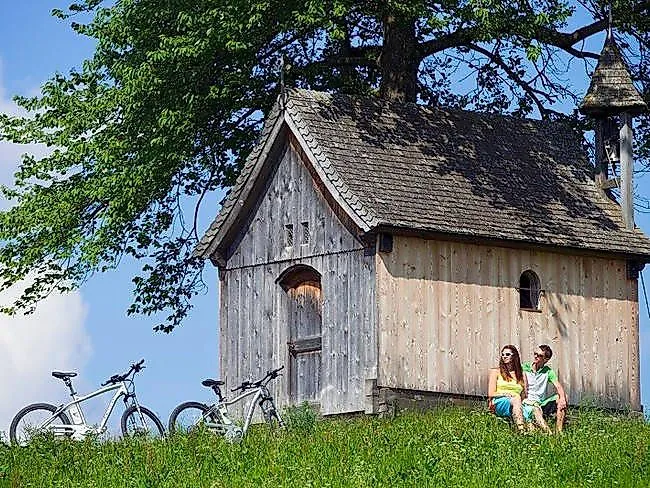 Dos e-bikers descansan en la idílica capilla de Kupfererkapelle, en la región plateada de Karwendel, cerca de Schwaz.