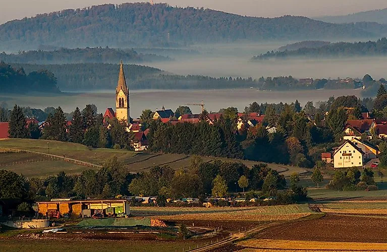 Pohled na Lautertal s kostelní věží v ranní mlze, zasazený do kopců a lesů
