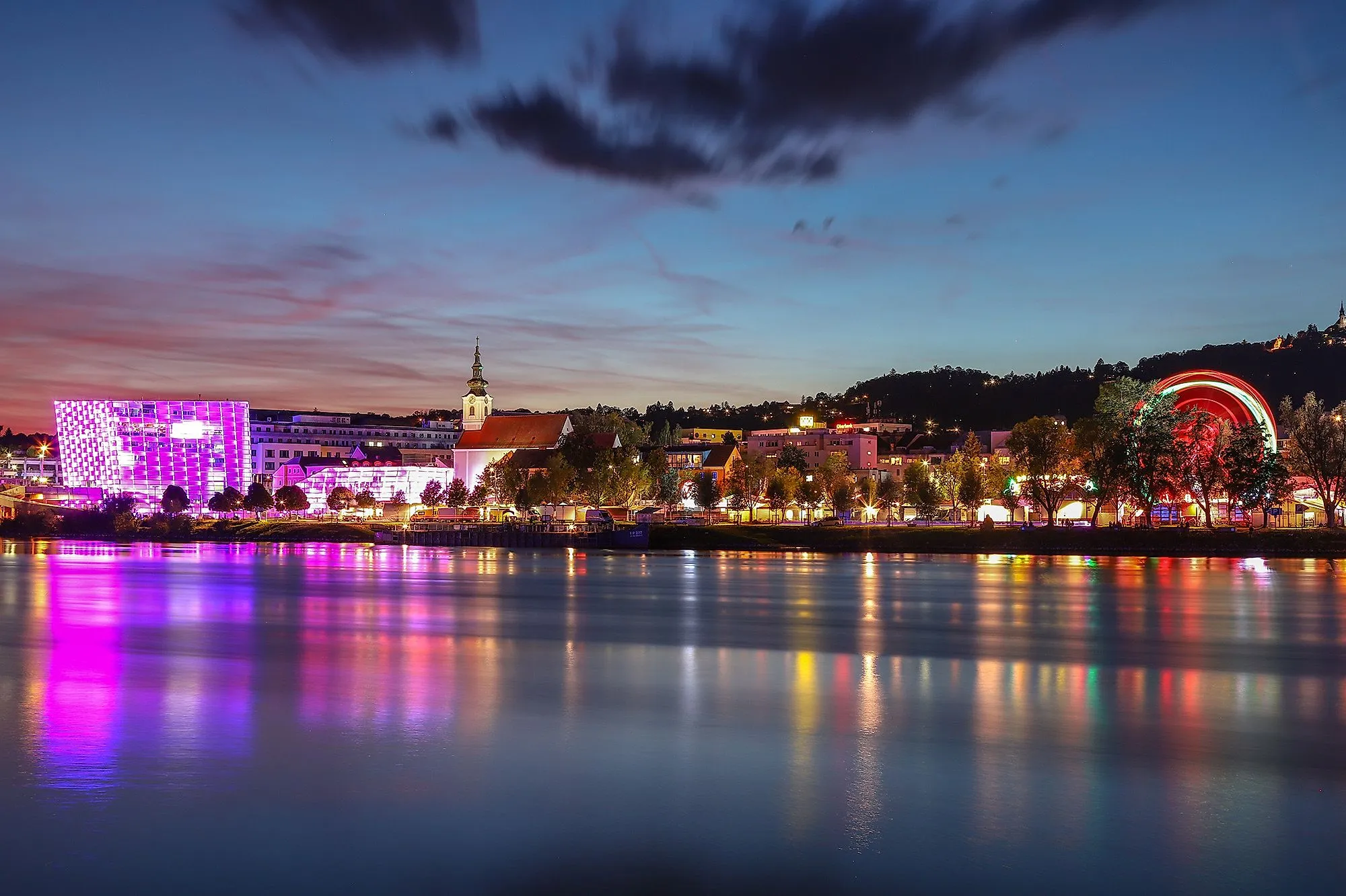 Photo de nuit de Linz avec le Danube, le centre Ars Electronica éclairé et la ligne d'horizon