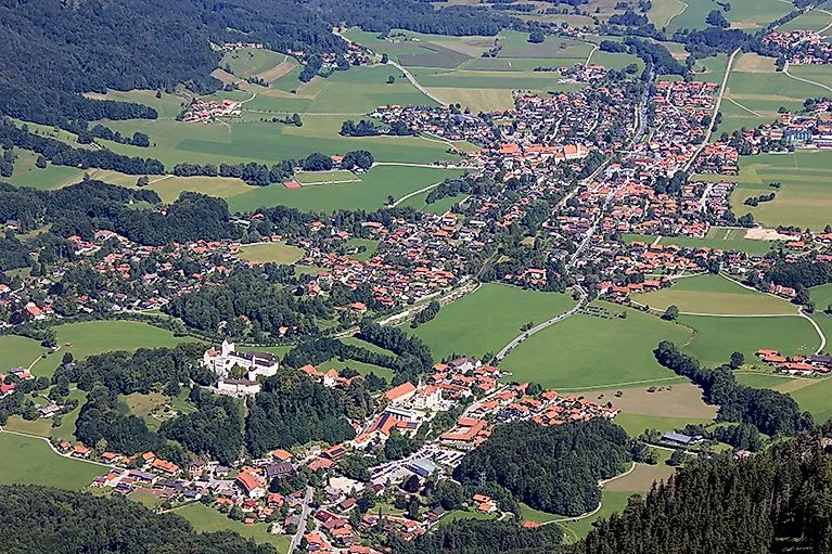 Blick auf Aschau im Chiemgau mit Schloss Hohenaschau, umgeben von grünen Wiesen und Wäldern.