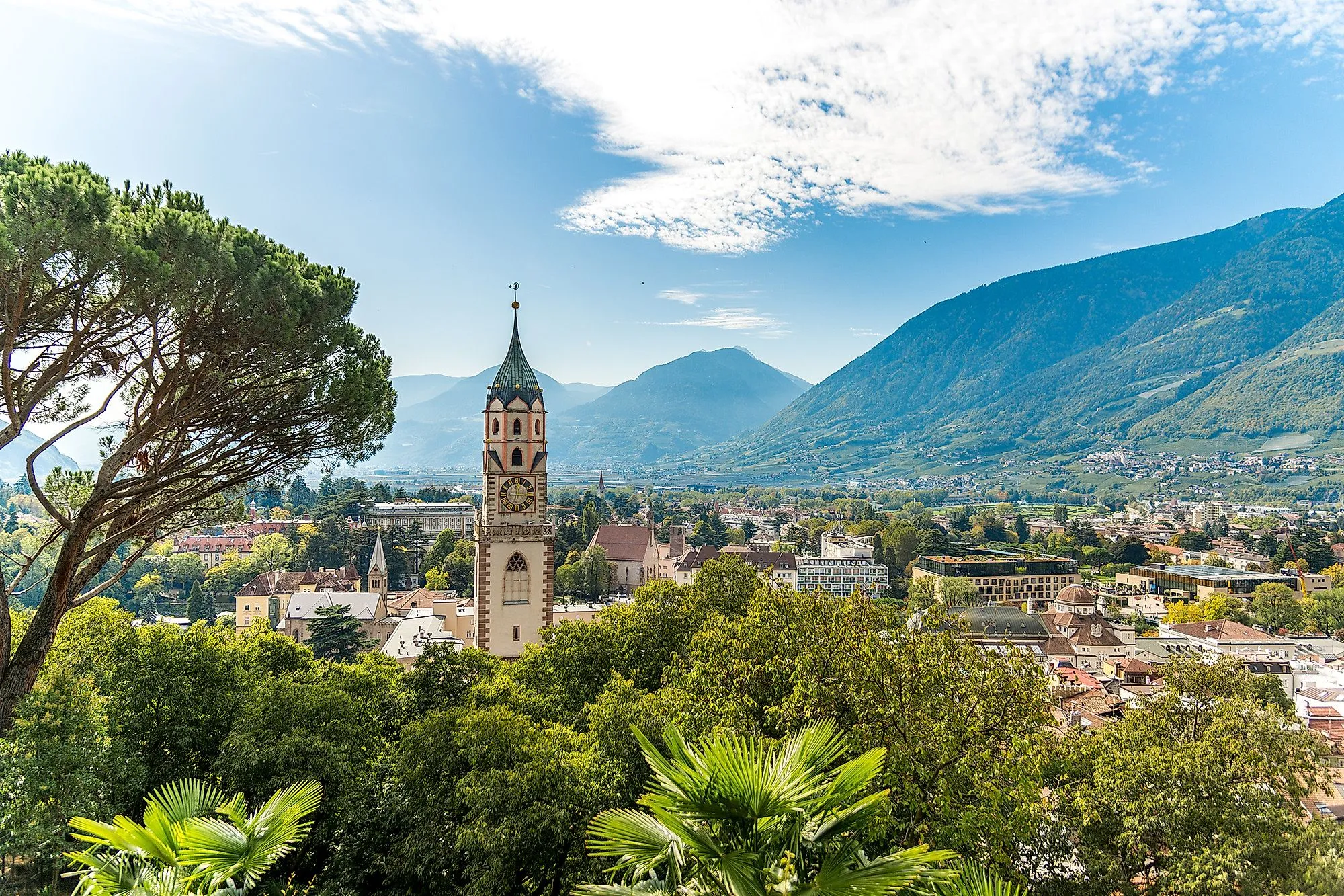 Panoramisch uitzicht op de stad Merano in Zuid-Tirol met kerktoren en omliggende bergen op een zonnige dag