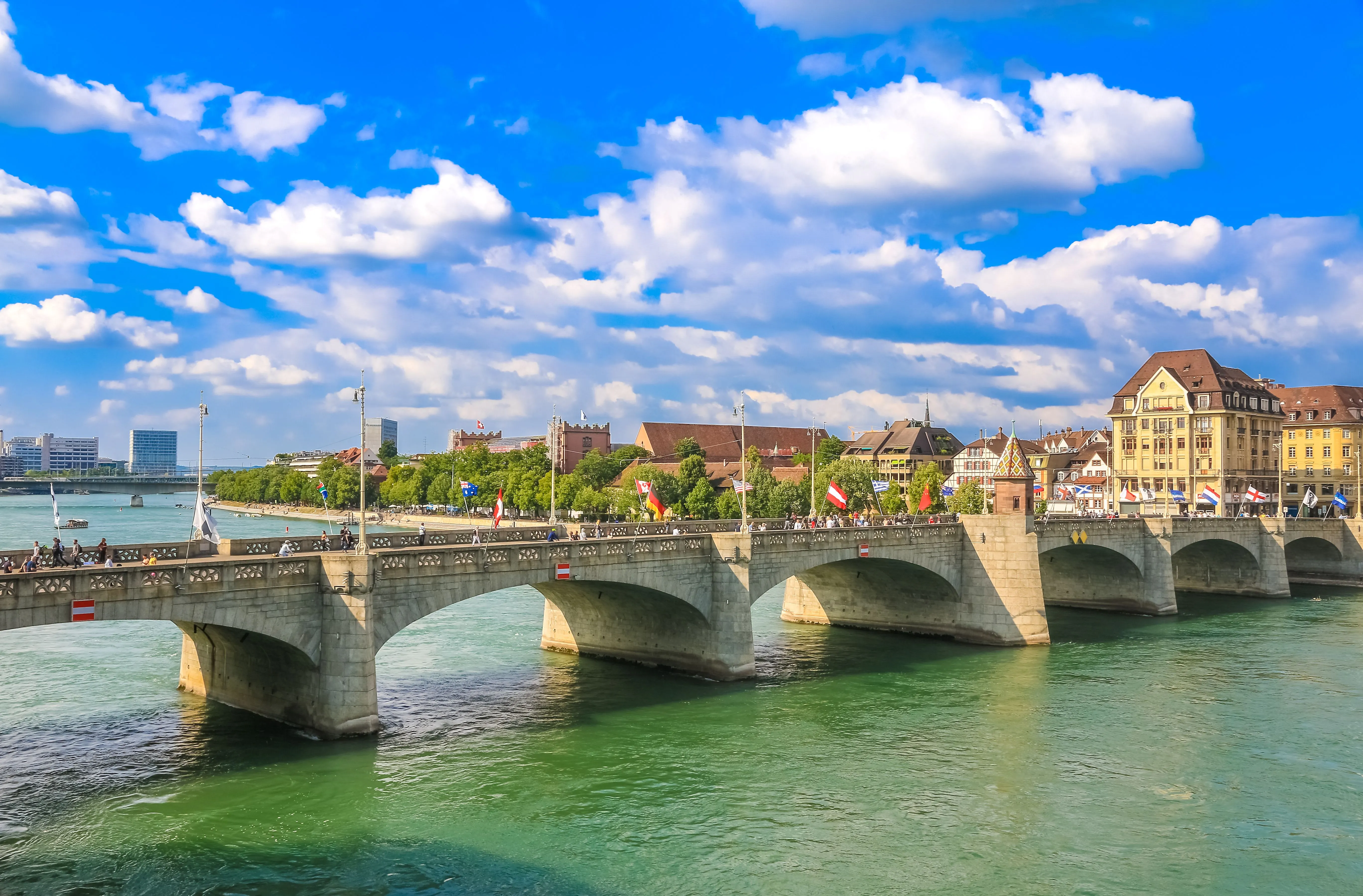 Vue sur le Mittlere Rheinbrücke avec les drapeaux flottant au vent et la vieille ville de Bâle par un jour d'été radieux