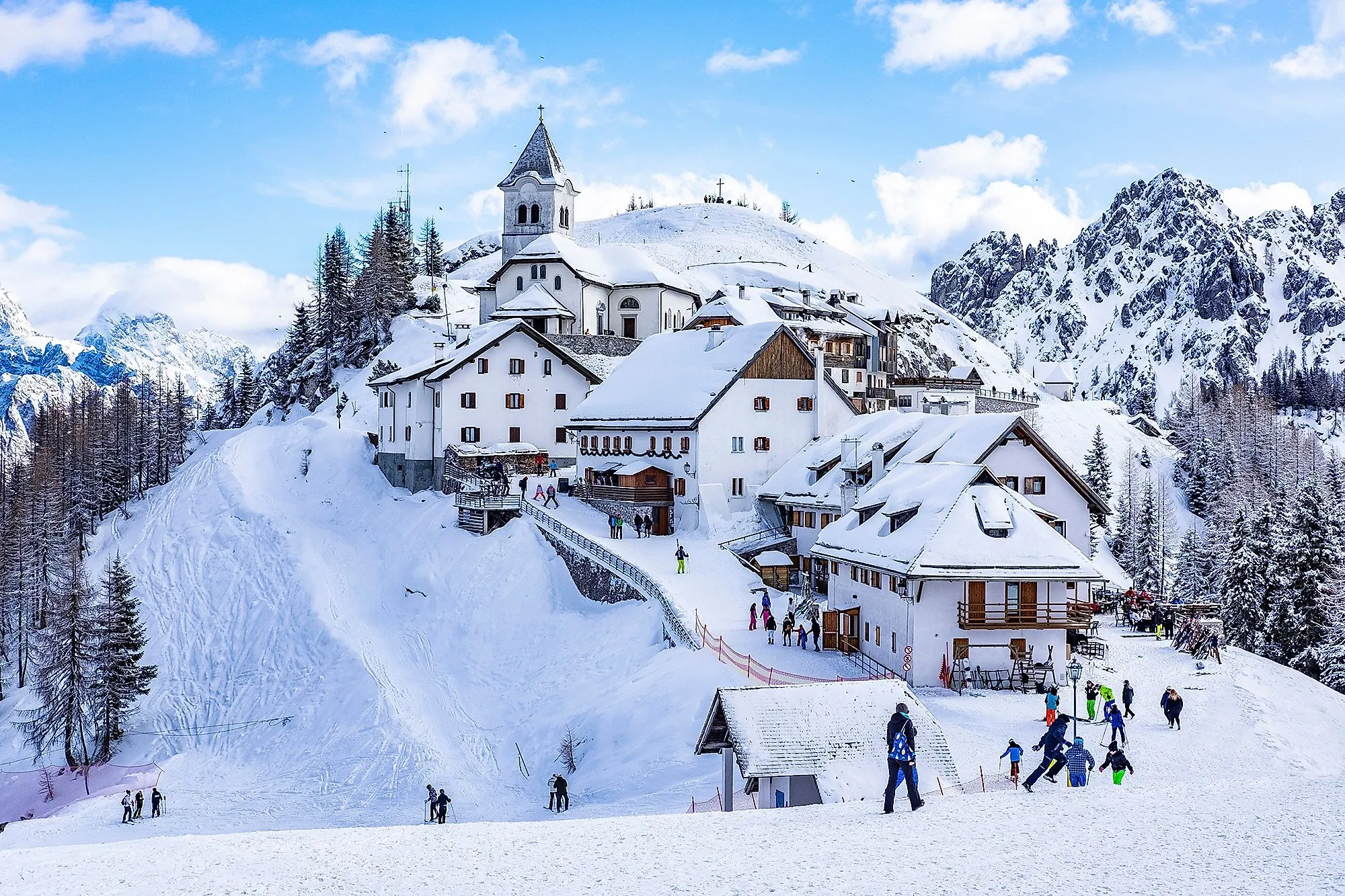 Zimné Monte Lussari so zasneženými domami a lyžiarmi v Tarvisiu
