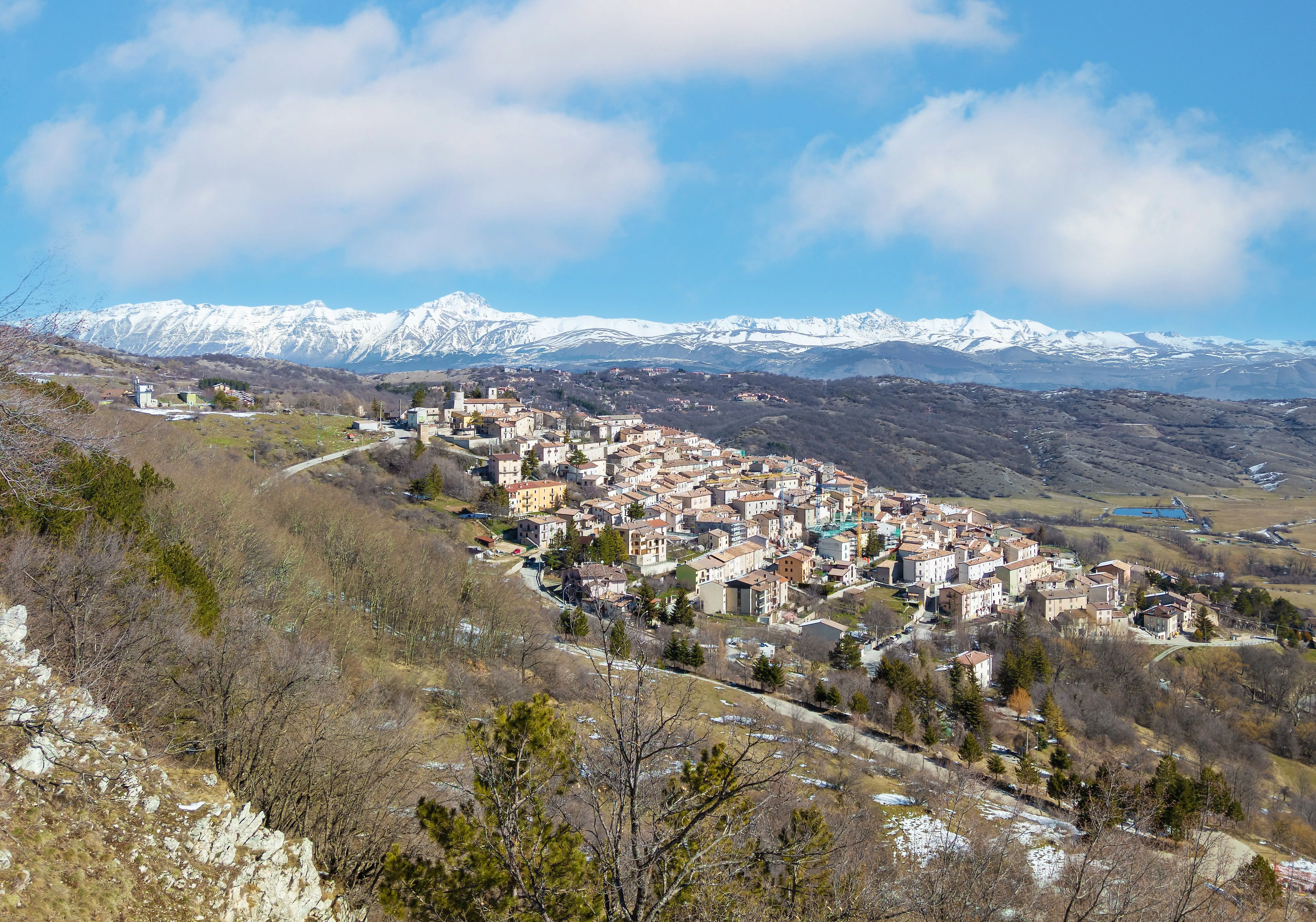 Bergdorf in den Abruzzen mit Blick auf schneebedeckte Gipfel und sanfte Hügellandschaft