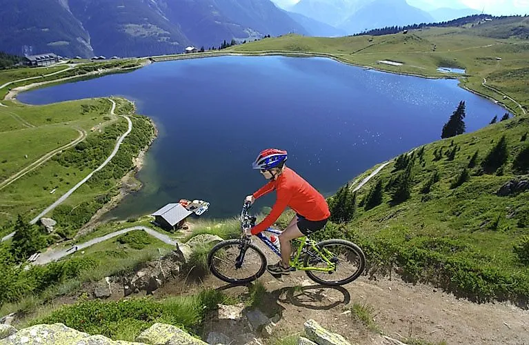 Mountainbiker fährt auf einem alpinen Trail oberhalb eines klaren Bergsees bei der Bettmeralp im Aletschgebiet.