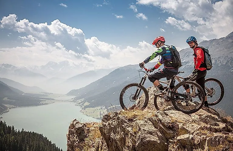 Twee mountainbikers genieten van het uitzicht over het meer van Reschen in Nauders.