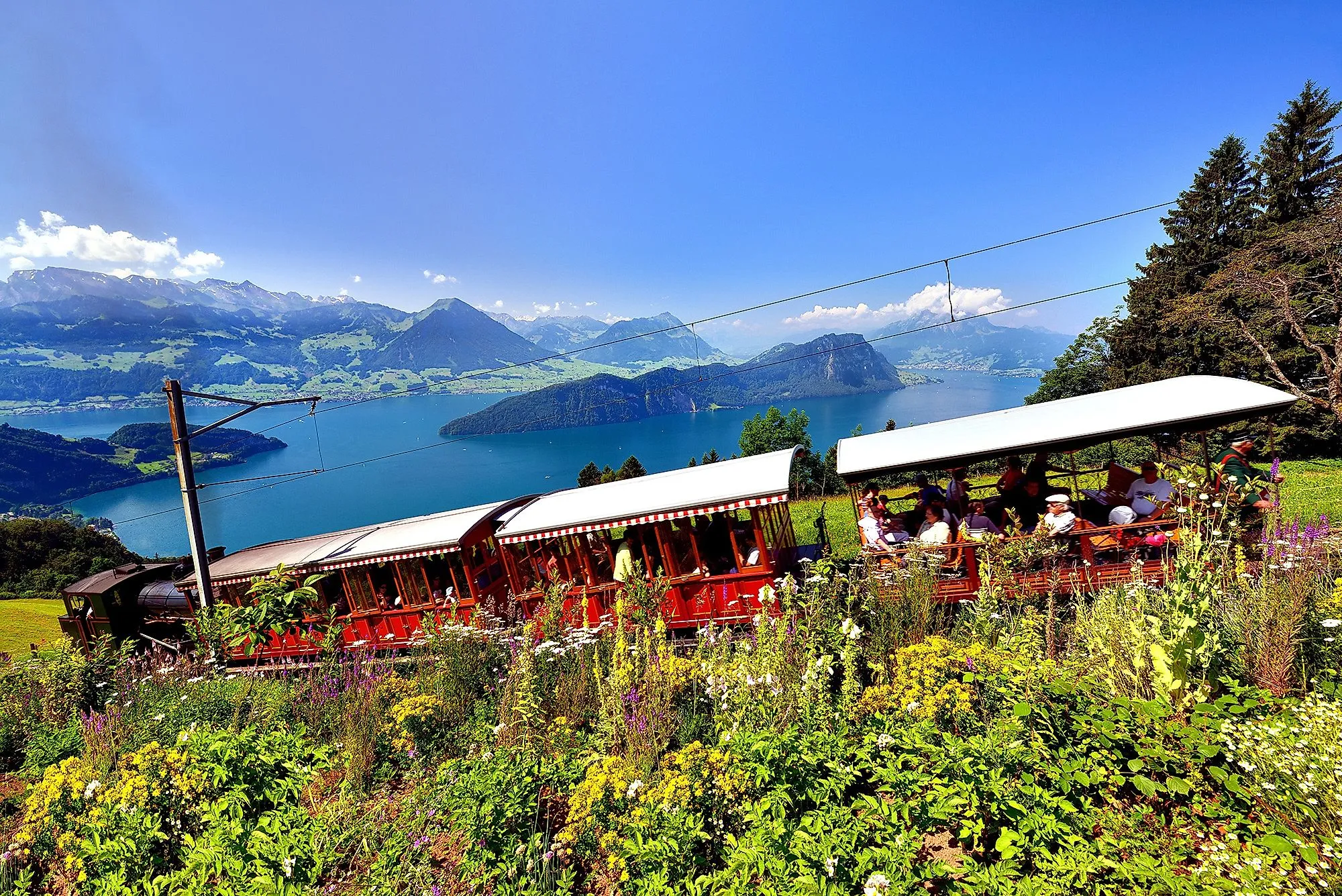 Červená ozubnicová železnica vedie pozdĺž Rigi s výhľadom na jazero Lucerne a hory