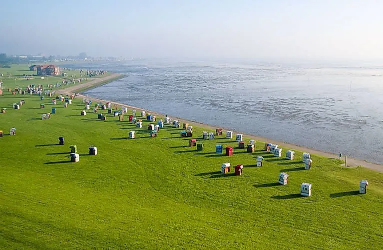 Green beach with numerous beach chairs on the North Sea coast near Horumersiel, view of the Wadden Sea at low tide