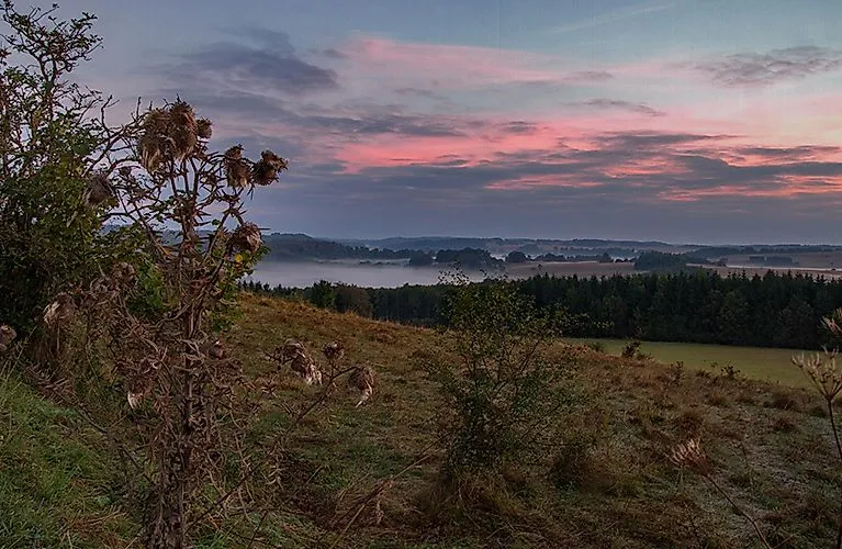 Atmosférická ranní krajina u Münsingenu na Švábském Albu s výhledem na mlhavé údolí Lauter.