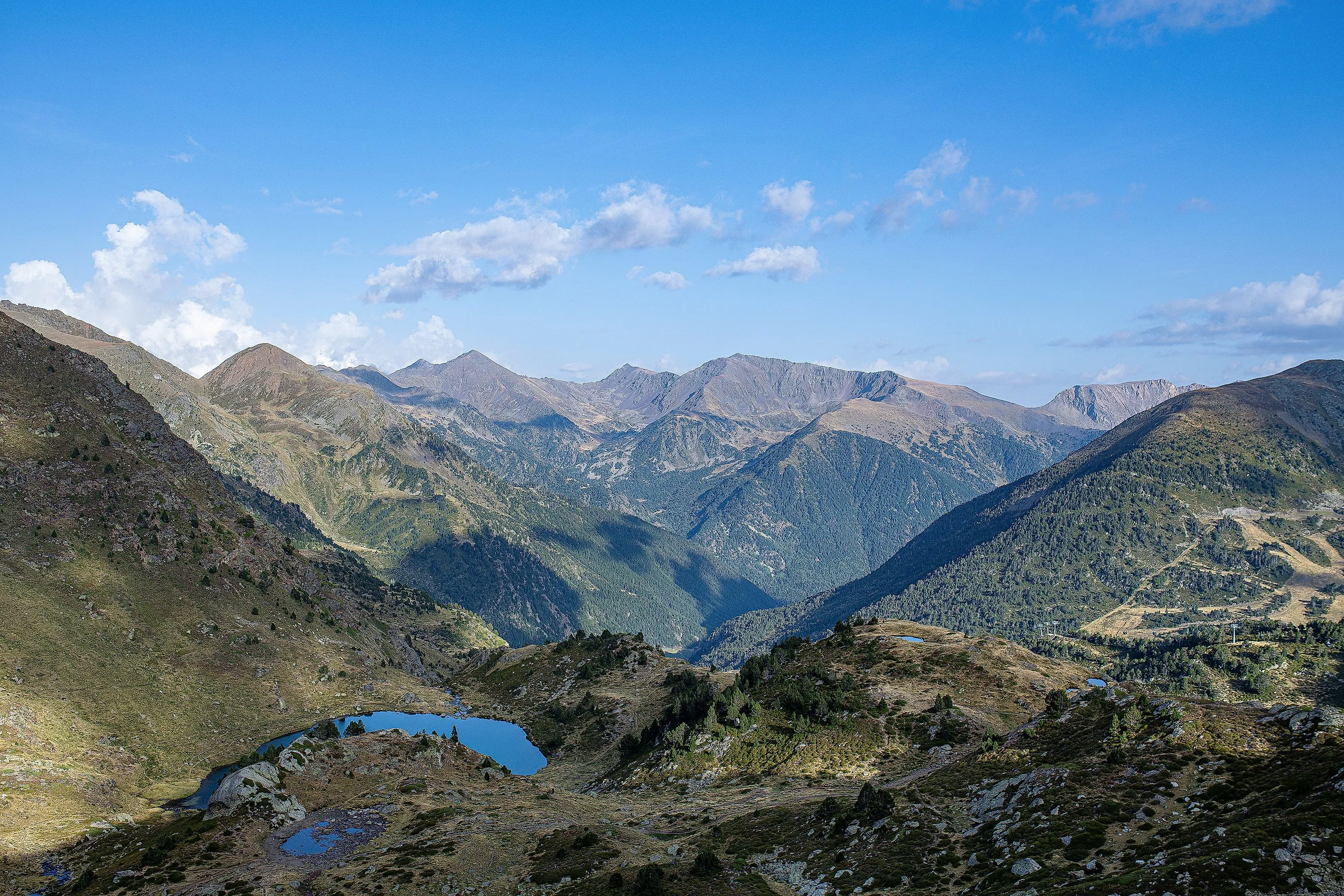 Tristaina-Seen in Andorra umgeben von grünen Bergen und blauem Himmel im Sommer